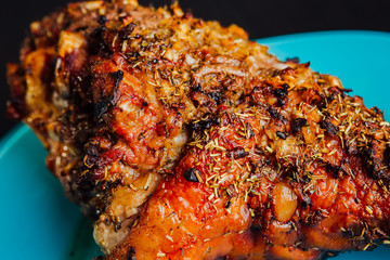 great fresh baked turkey leg and sliced piece sprinkled with spices lying on a blue plate to black wooden background