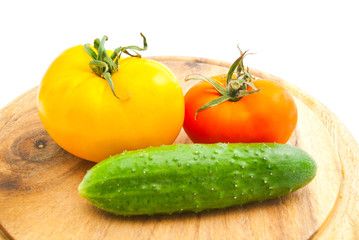 two tomatoes and cucumber on cutting board