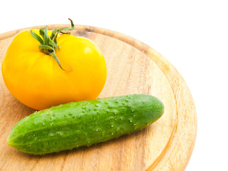 yellow tomato and cucumber on cutting board