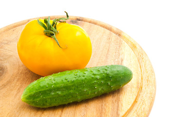 yellow tomato and cucumber on wooden cutting board