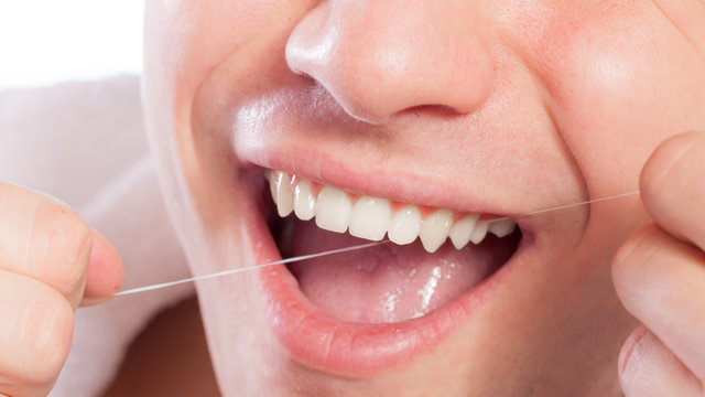 Young man cleaning her white teeth with dental floss