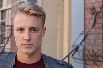 close portrait of handsome adult blonde man, with blured urban classic background