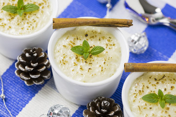 Rice Pudding with Cinnamon, New Year Ornaments in Blue Color, Pine cones and Candle