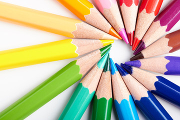 Set of multicoloured pencils lying on white table round order