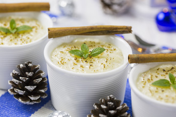 Rice Pudding with Cinnamon, New Year Ornaments in Blue Color, Pine cones and Candle