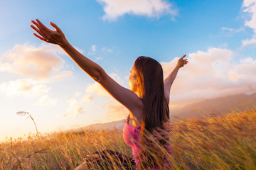 Girl raising arms towards beautiful glowing sunshine. 