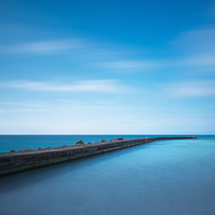 Fototapeta premium Concrete pier, rocks and sea on sunset. White beach, Tuscany, It