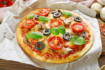 Tasty pizza with vegetables and basil on table close up