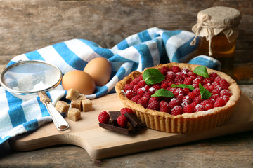 Tart with fresh raspberries, on wooden background