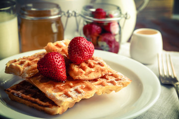Sweet homemade waffles with strawberries  on plate, on table background