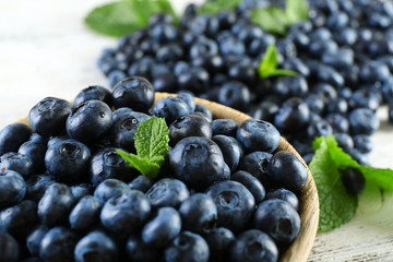 Tasty ripe blueberries with mint in bowl on table close up