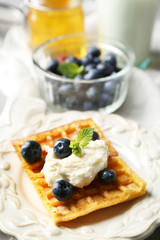 Sweet homemade waffles on plate, on color wooden background