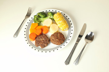 Hamburguesas acompañadas con vegetales cocidos.