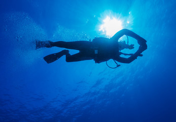 Silhouette of diver with sun disk behind