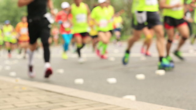 defocused marathon runners running on city road