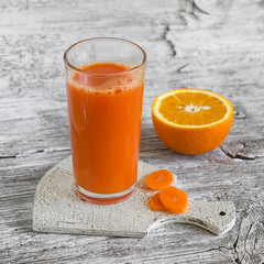 carrot-orange juice in a glass beaker on a light wooden background