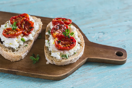 sandwich with goat cheese, sun-dried tomatoes and thyme, served on the Board at a bright wooden surface