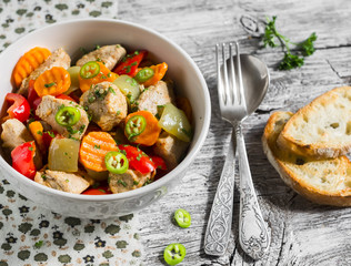 meat stew with vegetables - carrots, onions and sweet peppers in a white bowl on a light wooden background