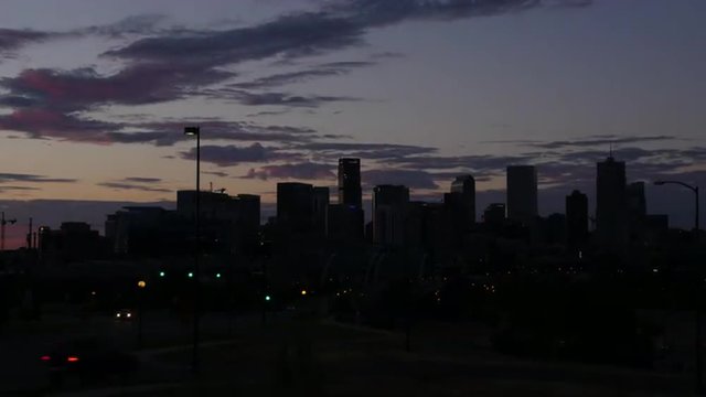 Sunrise over downtown Denver, Colorado skyline, with traffic and red clouds.
