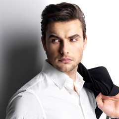 Fashion young man in white shirt holds the black jacket