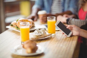 Cropped image of woman using phone while having breakfast 