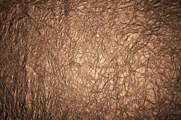 Close up of wrinkled textured metallic bronze grunge background with dark vignette shadowing