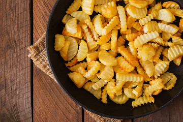 Frying pan with a fried potato in a rural way on a wooden background