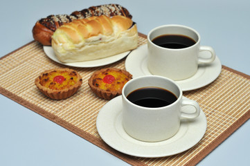 hot coffee with coconut tart and red bean bread on bamboo mat