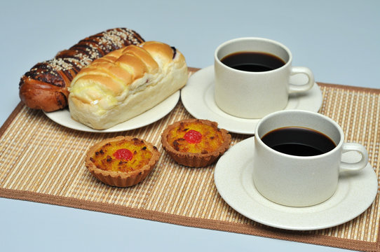 hot coffee with coconut tart and red bean bread on bamboo mat