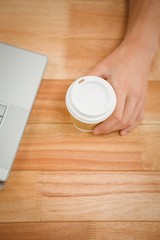 Man holding disposable cup on table in office