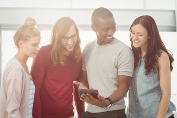 Obraz premium Smiling man showing digital tablet to coworkers 