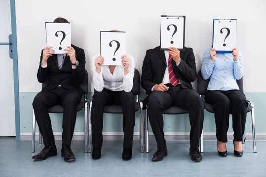 Businesspeople Hiding Behind Question Mark Sign