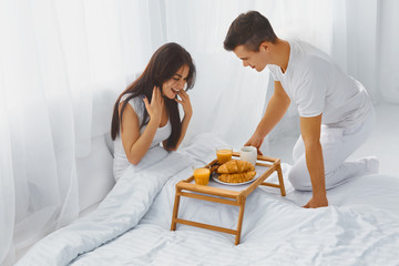 Man surprising woman with breakfast in bed