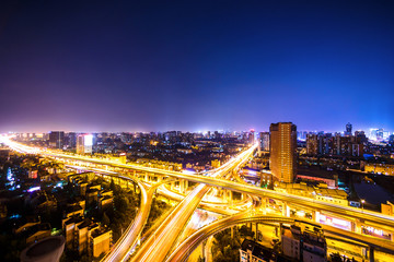 Obraz na płótnie Canvas busy traffic on viaduct among modern skyscrapers at night