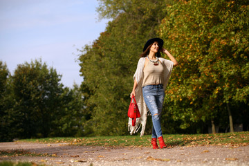 Young woman in fashion blue jeans and red bag walking in autumn