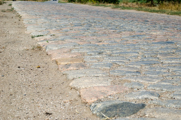 Old cobblestone road paved with urban stones