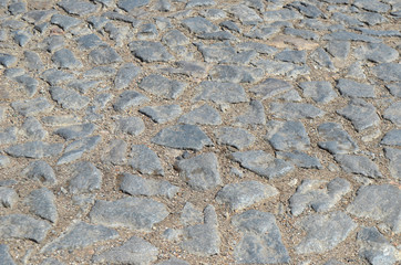 Old cobblestone road paved with urban stones