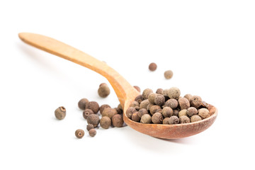 Aromatic allspice in wooden spoon. Isolated on white background.