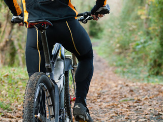 Cyclist standing in front of a path of the forest