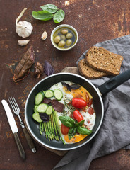 Pan of fried eggs, salami, asparagus, cherry-tomatoes with bread