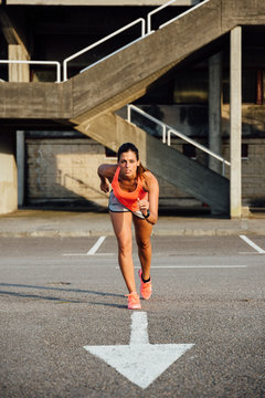 Female athlete starting to run on urban asphalt. Sporty woman running and working out outdoor.