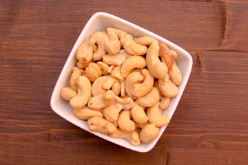 Cashew nuts on bowl on wooden table seen from above