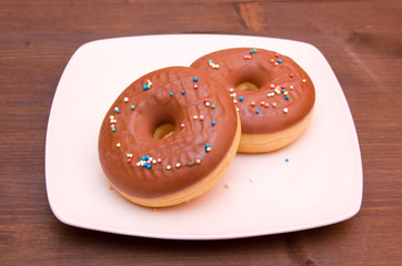 Donuts with chocolate and colored sugar on wooden table
