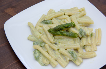 Pasta with cream of asparagus on wooden table close up view