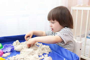 Fototapeta premium Cute little boy age of 2.11 years plays kinetic sand