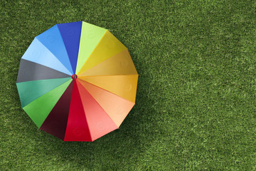 Euro currency units on colourful umbrella on green grass