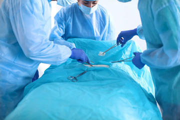 Team of surgeon in uniform perform operation on a patient at