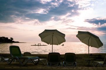 pink sky above sea and two sunshades