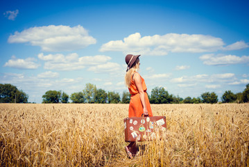 Charming elegant girl wearing hat holding suitcase in summer