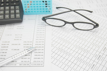 Silver pen have spectacles and calculator with blue pencil basket